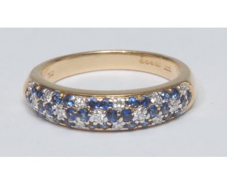 A sapphire and diamond ring, rounded panel of thirty two blue sapphires and seventeen round brilliant cut diamonds arranged i