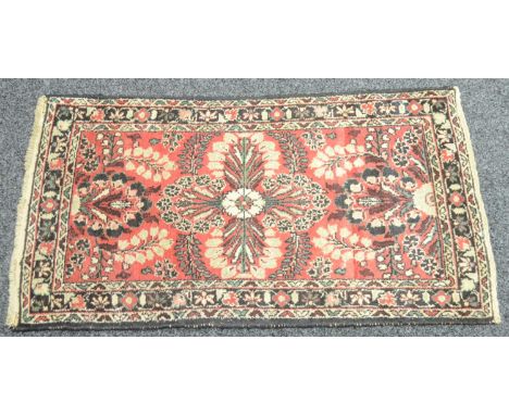 A Middle Eastern woollen carpet, in traditional tones of red, cream, black  and blue, with a geometrical patterns, 133cm x 73