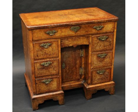 A George I walnut kneehole desk, rounded rectangular quarter-veneered crossbanded top above a long frieze drawer, flush drawe