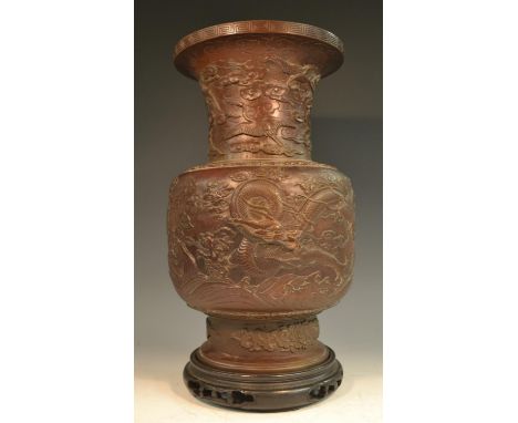 A Chinese brown-patinated bronze baluster vase, cast in relief with ferocious dragons and scroll clouds, the neck with cranes