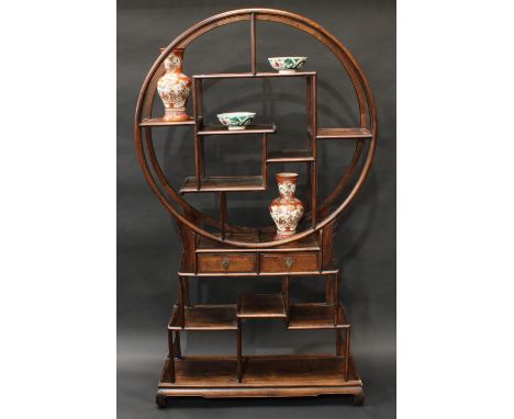 An unusual Chinese hardwood open porcelain cabinet, circular superstructure with an asymmetric arrangement of plateaus, the b