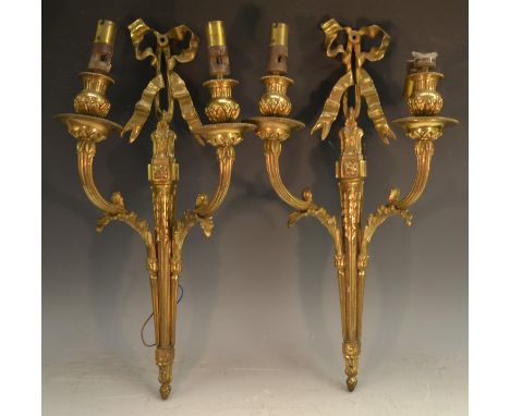 A pair of Neo-Classical design gilt metal two-light wall lights, ribbon tied, campana shaped sconces, acanthus wrapped reeded