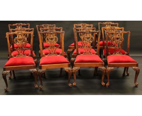 A set of twelve Chippendale Revival dining chairs, boldly carved throughout, crimson drop-in seats, acanthus scrolling cabrio