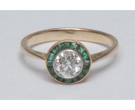 A diamond and emerald cluster ring, central round brilliant cut diamond approx 0.50ct, surrounded by a collar of irregular cu