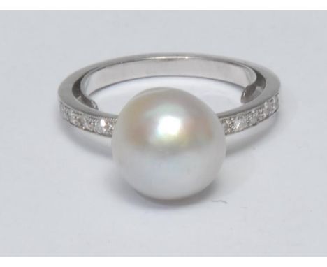 A pearl and diamond ring, large creamy silver white cultured pearl, approx 11mm diameter, above ten stone diamond inset shoul