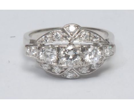 An Art Deco style diamond cluster ring, multilevel platform inset with three larger central round brilliant cut diamonds abov