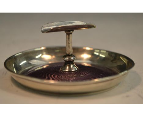 An early 20th century silver and enamel cigar rest, the dished base decorated in tones of mauve on an engine turned ground, 7