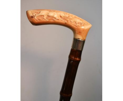 A late 19th century German gentleman's silver-mounted ivory and bamboo walking stick, the handle carved in relief with a gun 