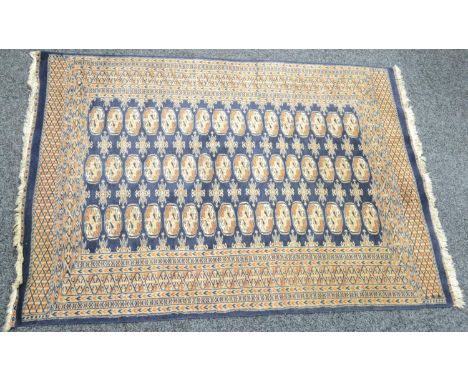 A Middle Eastern woollen carpet, in traditional tones of blue, tan and white, with a geometrical patterns, 180.5cm x 128cm