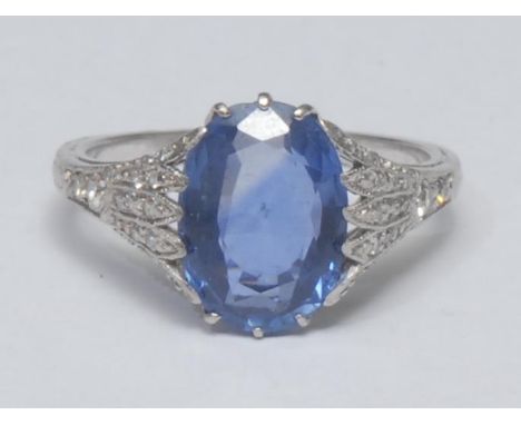 A sapphire and diamond ring, large oval purpley blue sapphire approx 3.5ct, diamond inset floral shoulders, unmarked whilte m