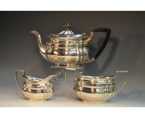 A George V silver three piece shaped oval tea service, comprising teapot, milk jug and sugar basin, fluted angles, the teapot