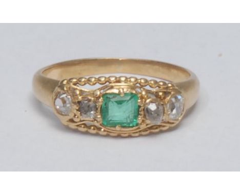 An emerald and diamond childs ring, central square cushion cut emerald approx 0.16ct, flanked by a pair of old cut irregular 