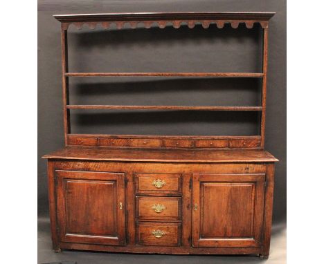 An 18th century oak dresser, the plate rack with outswept cornice above a shaped frieze, open shelves and six spice drawers, 