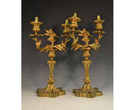 A pair of 19th century ormolu two-light table candlesticks, cast with leafy scrolls, fluted columns, shaped bases, with stiff