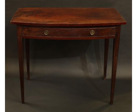 A George III/IV mahogany bow fronted side table, oversailing top above a frieze drawer, tapered square legs, brass ring handl