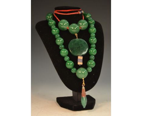 A string of thirty-six graduating Chinese green jade beads, the largest with a suspended droplet, 28cm drop; a Chinese green 