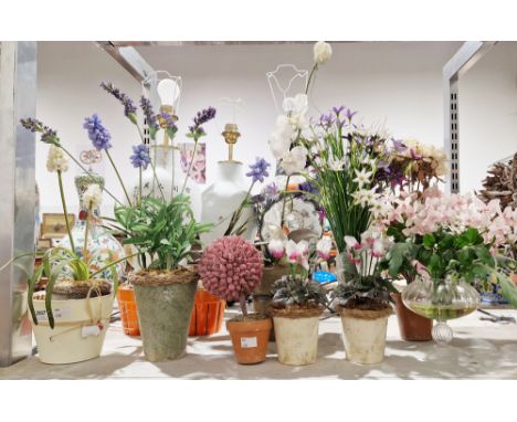 A quantity of faux floral arrangements the majority contained within ceramic or glass planters to include geraniums, lavender