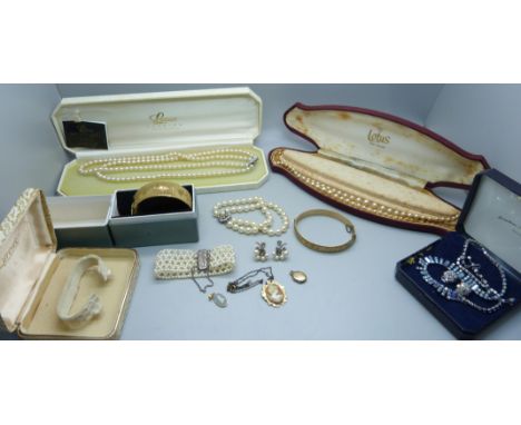 A collection of costume jewellery including strings of pearls, two with silver clasps, a pair of pearl earrings, a rolled gol