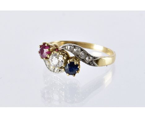 A pretty Art Deco period three stone crossover ring, having an old cut diamond, sapphire and ruby and heightened by four old 