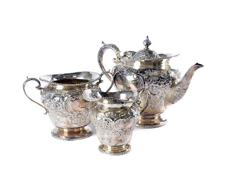 A late Victorian silver three piece tea set by HA, large form teapot, sugar basin and milk jug with embossed scroll and leaf 