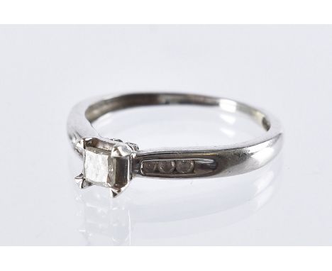 A modern 9ct white gold and diamond engagement ring, having a central princess cut stone and channel set small brilliant cuts