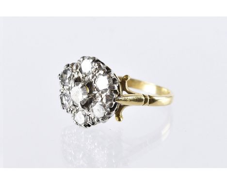 A vintage diamond cluster dress ring, the platinum flower head tablet set with seven brilliant cuts, on an 18ct gold band, 5.