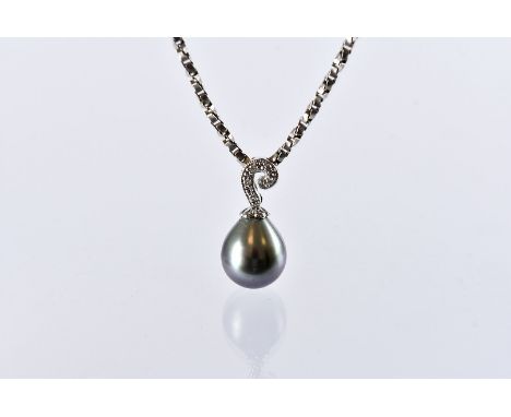 A modern 18ct white gold and black pearl pendant, heightened with diamonds to the scroll bale, supported on a silver chain ne