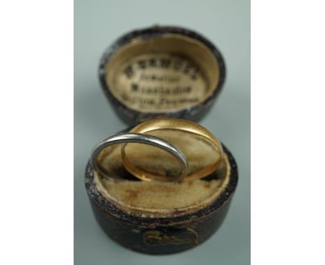 An 18 ct gold wedding band, .89 g, together with a precious white metal band stamped "Plat", 2.1 g, in an antique ring case