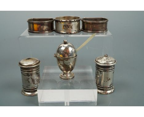 A pair of 1920s D-section silver napkin rings, one other silver napkin ring and a silver three-piece cruet set