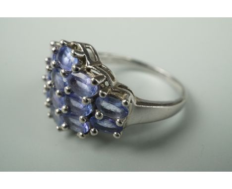 A contemporary dress ring, the face set with rows of pale purple coloured stones, stamped 935 and tested as silver, size R 1/