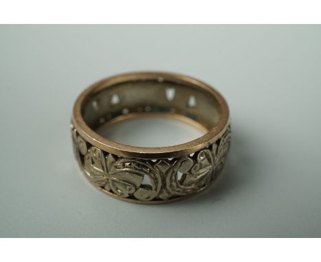 A two-colour yellow metal wedding band, fretted and engraved in a scroll and blossom pattern, O, stamped 9 ct, 4.2 g