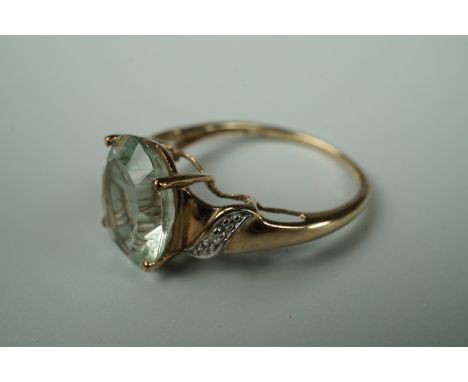 A contemporary pale green aquamarine and diamond dress ring, having a central oval-cut aquamarine flanked by decorative scrol