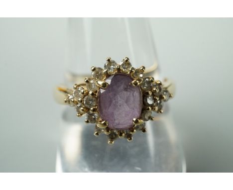 A contemporary diamond and amethyst dress ring, having a central oval cut amethyst of .9ct, framed and flanked by twenty bril