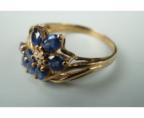 A contemporary diamond and blue spinel cocktail ring, the face set with a flower spray, comprising spinel petals surrounding 