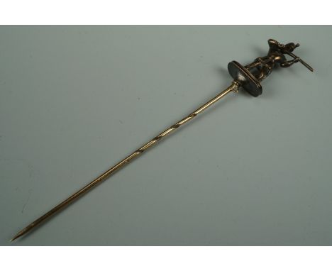 A Victorian yellow metal stick pin, its terminal in the from of a British army soldier wearing a shako and shouldering a rifl