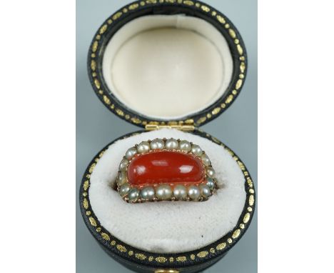 A Georgian carnelian and pearl finger ring, comprising a contoured rounded oblong carnelian cabochon set within a frame of pe