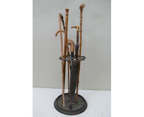 A CAST METAL STICK STAND CONTAINING A VARIED SELECTION OF WALKING STICKS and an Oriental parasol 