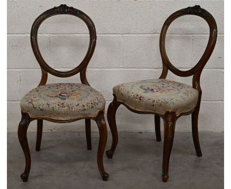 A pair of Victorian carved walnut side chairs with floral tapestry seats and cabriole front legs
