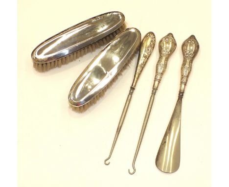 Two silver-backed clothes brushes, two silver-handled button hooks and a shoe horn, (5).