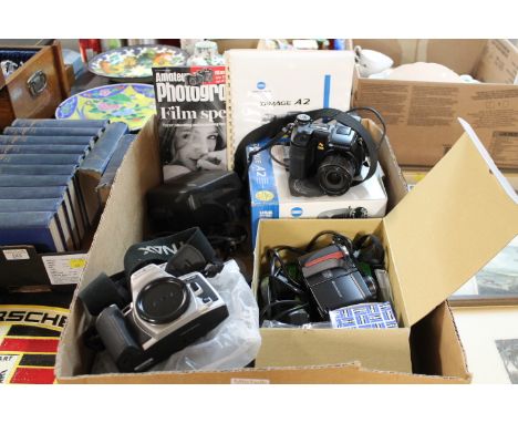 Three boxed digital cameras, Nikon Coolpix, Konica Minolta and Dynax Super, and Polaroid camera