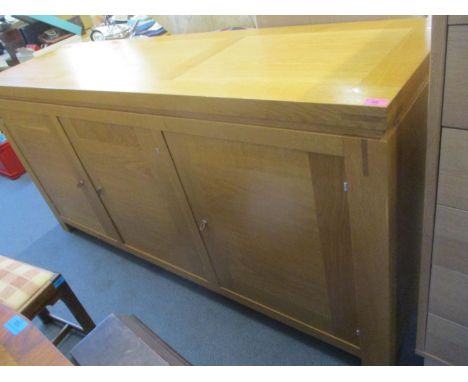 A modern light oak sideboard having three cupboard doors and standing on block feet, 34" h x 71"w 