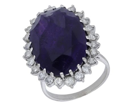 An amethyst and diamond cluster ring, the oval mixed-cut amethyst in a raised claw setting within a surround of brilliant-cut