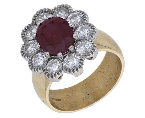 An 18ct gold ruby and diamond cluster ring,  the oval mixed-cut ruby within a surround of brilliant-cut diamonds, to a broad 