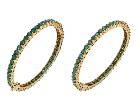 A pair of emerald bangles, each hinged bangle claw-set with a continuous row of circular-cut emeralds, inner diameter 6cm.  £