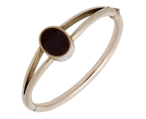 A hardstone bangle, circa 1900, set with an oval hardstone plaque engraved with scrolling ‘LW’ monogram, the bifurcated shoul