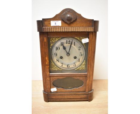 An early 20th century oak cased mantel clock, having carved decorations, brass spandrels to dial, with pendulum and key.