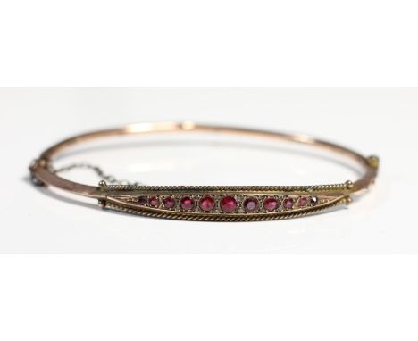 An Edwardian 9ct rose gold and garnet bangle, Chester, date letter worn, as found, internal 6 x 5cm, 4.2gm 