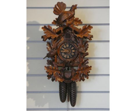 A German Bavarian softwood cuckoo clock with cast metal pine cone weights, 48 x 30cm.