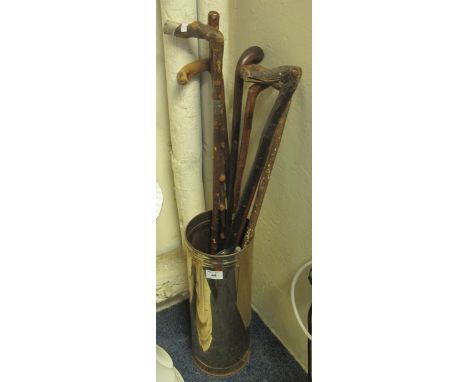 Brass cylindrical umbrella stand containing assorted rustic and hardwood walking sticks and a weighted swagger stick. (9)(B.P