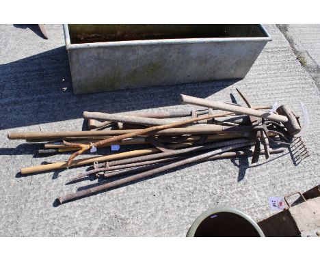 A mixed collection of garden tools. Noting pitchforks, shovels, sickle and a quantity of iron bar etc.
